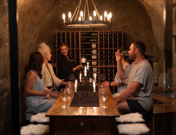 Group doing a seated wine tasting experience inside Gibbston Valley Winery's cave. 