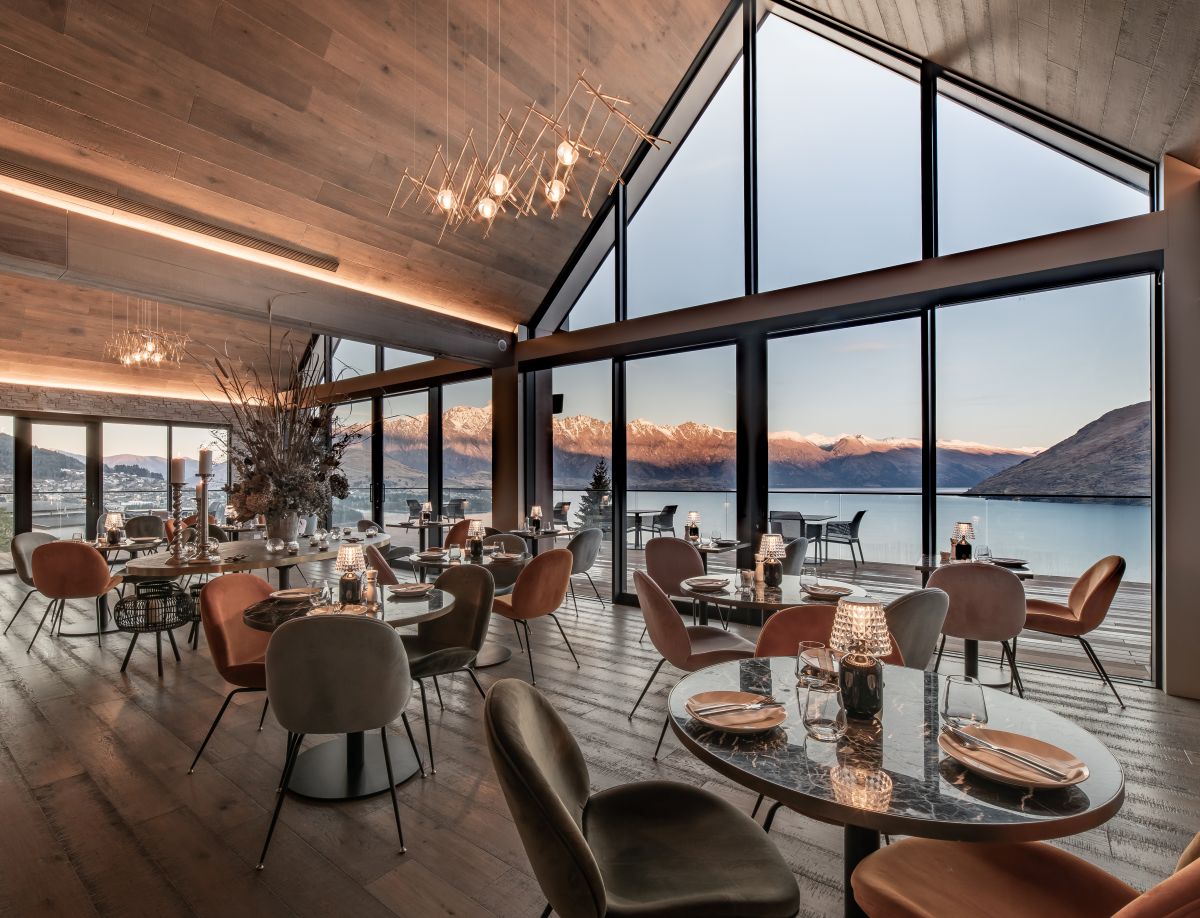 Nest Restaurant tables and chairs set up with floor to ceiling windows overlooking Lake Whakatipu and the Remarkables.