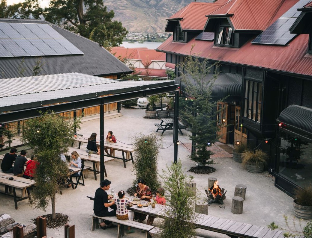 View of Sherwood Hotel courtyard area. People sitting on picnic tables.