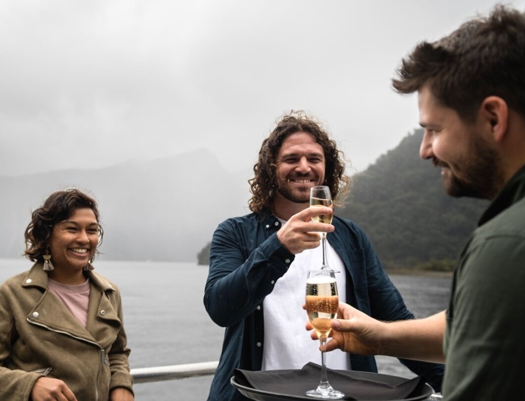 Three people drinking bubbles on a Milford Sound cruise