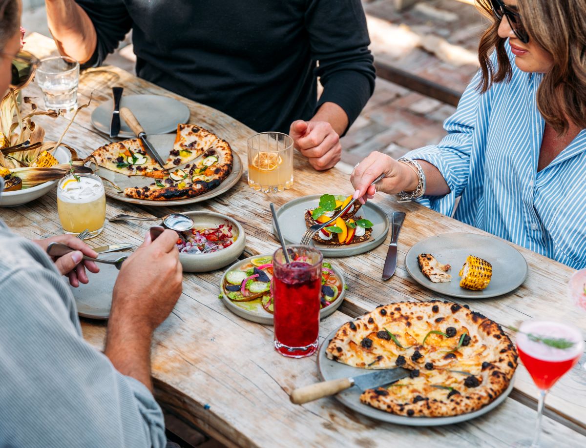 People eating pizzas on outdoor table at Sherwood.