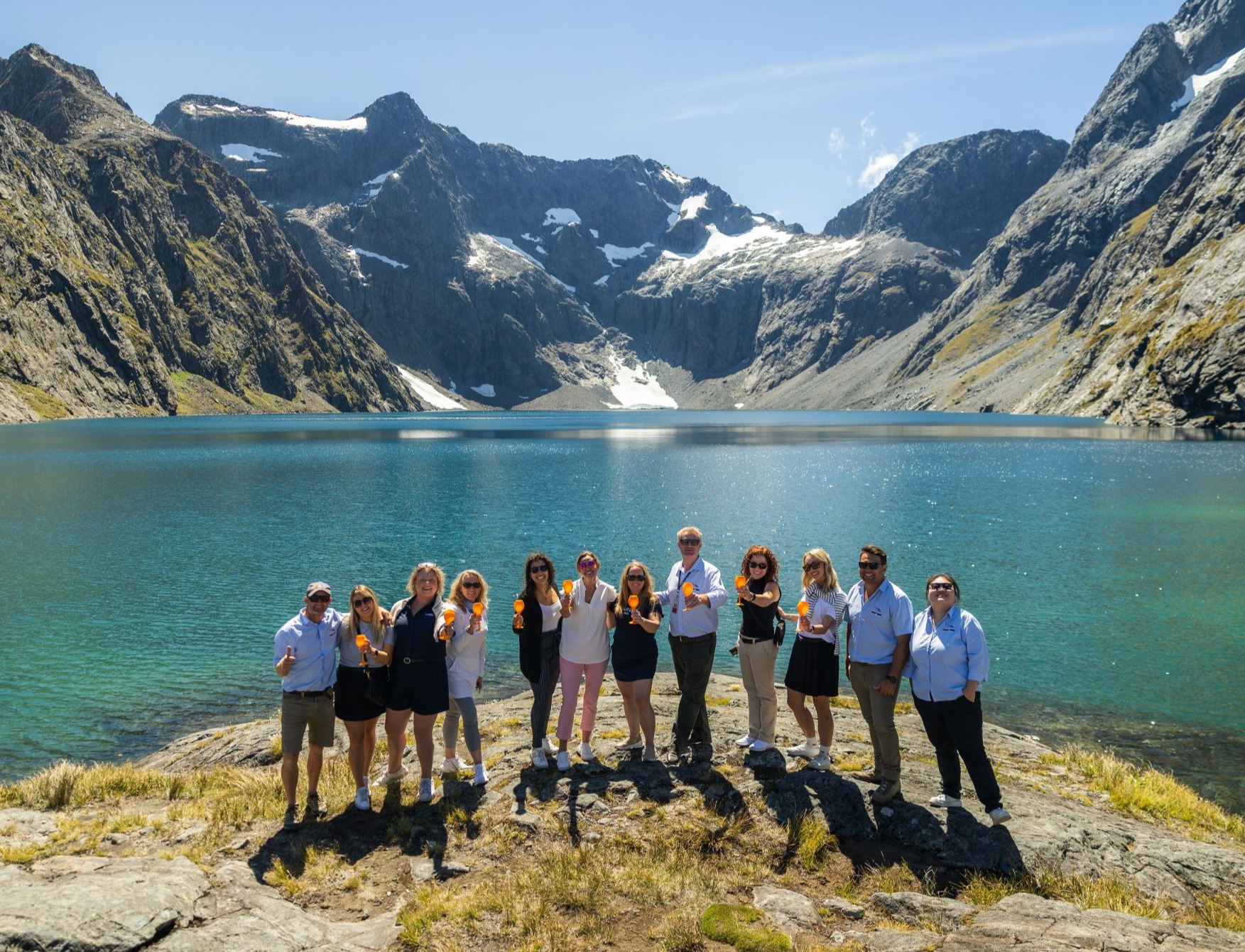 Famil group posing for a photo holding a glass of bubbles in front of Lake Erskine.
