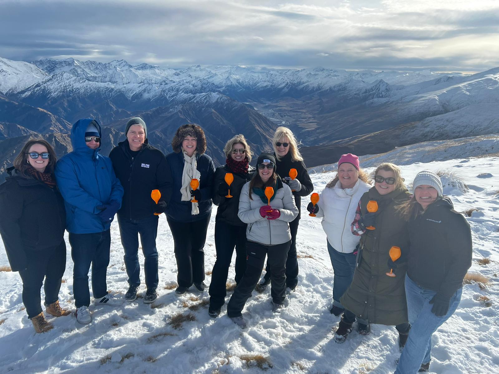 Group on a mountain top with a glass of bubbles.